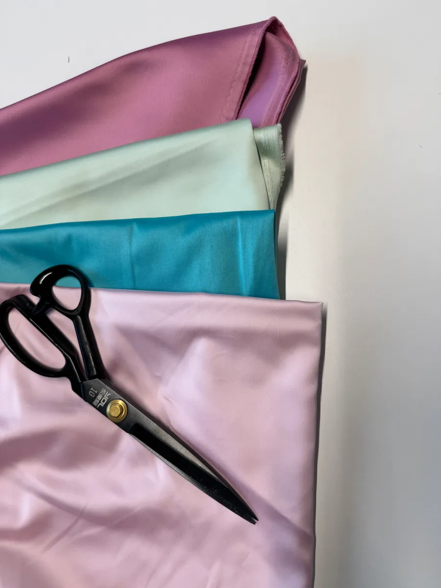 Satin fabric swatches in pink, teal, mint and mauve with tailor's shears